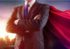 Businessman wearing a cape, standing confidently.