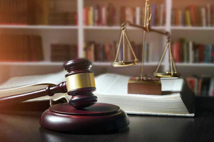 648441076 Gavel, law book, and scales in a library.