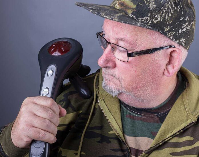 Elderly man in camouflage clothing holding a handheld device