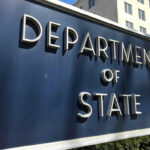 Department of State sign in front of building.