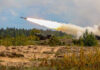 Military tank firing a missile in forest area.