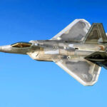 Fighter jet in flight against a clear blue sky.