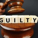 A gavel above wooden blocks spelling 'GUILTY'