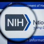 NIH logo displayed on a digital screen, viewed through a magnifying glass