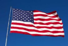 American FLAG Flies AGAIN After 7 LONG YEARS Waving American flag against a clear blue sky