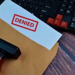 A 'DENIED' stamp on a rejection notice placed on a desk