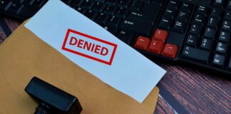 A 'DENIED' stamp on a rejection notice placed on a desk