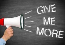 Trump Demands Surrender—Tehran Counters HARD A hand holding a megaphone with the words GIVE ME MORE on a blackboard background