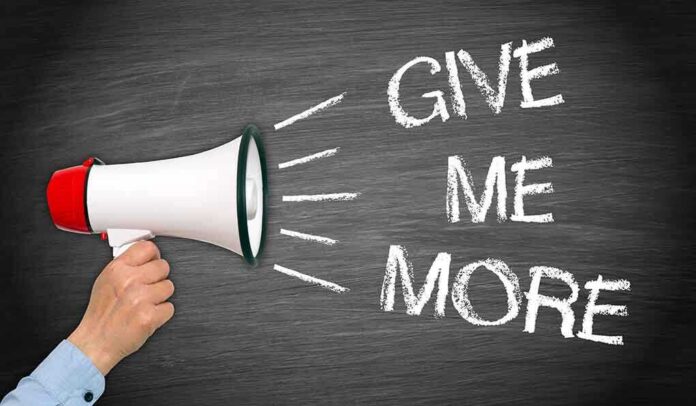 shutterstock_233849815.jpg A hand holding a megaphone with the words GIVE ME MORE on a blackboard background