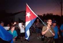 Cuba Blinks On-Air: Trump Talks A group of people participating in a protest march holding a Cuban flag