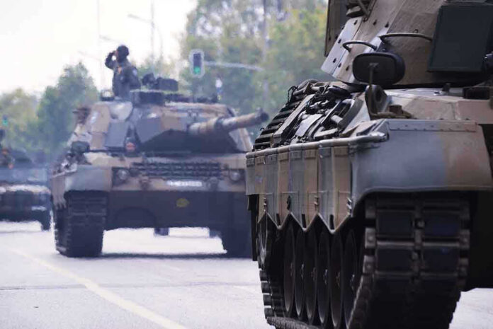 Tanks on a road with soldiers inside.