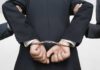 Three Democratic Officials ARRESTED – Child Abuse Crimes A person in a suit with hands cuffed behind their back