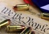 Close-up of bullets surrounding a historical document with the phrase We the People