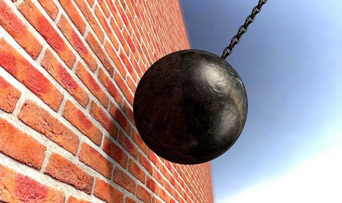 A wrecking ball suspended near a brick wall, suggesting demolition activity