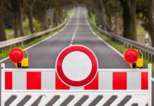 Traffic barrier with a red and white sign blocking a road