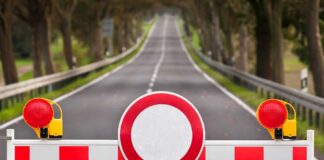 Traffic barrier with a red and white sign blocking a road