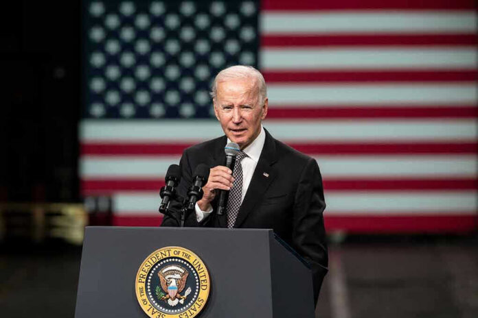 Man speaking at podium with US flag background.