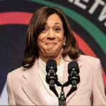 Fear Wave Exposed: Fear, Symptoms, and the Pandemic Debate Woman smiling behind two microphones on a podium.
