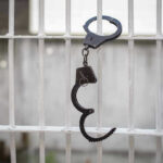 Former PM’S Release Sparks OUTRAGE — ELITES Above Law? Handcuffs hanging on a barred window.