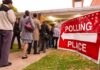 POPULATION CAP Vote PUSHED THROUGH People waiting in line at a polling place with a sign indicating direction