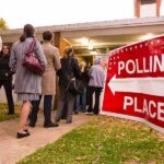 POPULATION CAP Vote PUSHED THROUGH People waiting in line at a polling place with a sign indicating direction