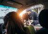 Masked criminal reaching through car window attempting to rob occupants inside vehicle on rainy day