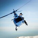 Shocking Rescue: Toddler Trapped On Mountain A helicopter flying over a mountainous landscape against a blue sky