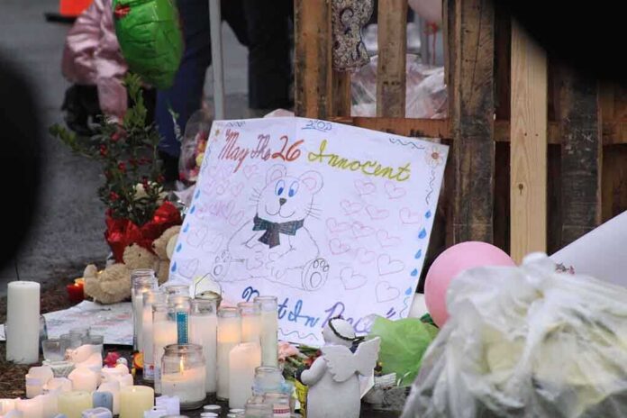 A memorial site with candles, flowers, and a hand-drawn poster