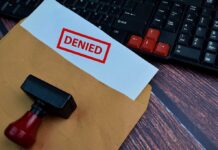 A 'DENIED' stamp on a rejection notice placed on a desk