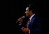 Man in a suit speaking into a microphone on stage