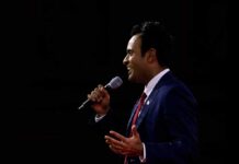 Man in a suit speaking into a microphone on stage