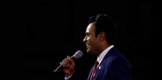Man in a suit speaking into a microphone on stage