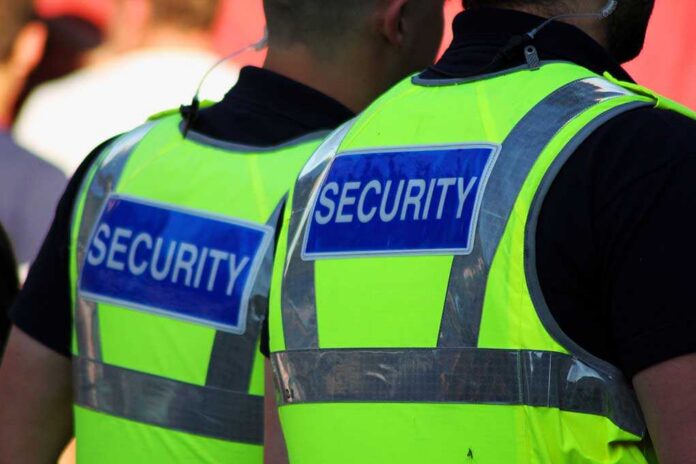 Two security personnel wearing high visibility vests with SECURITY printed on the back