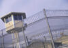 Guard tower behind barbed wire fence in a prison.
