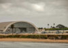 Military Power Meets Humanitarian Crisis Aircraft hangar with helicopters near the beach.