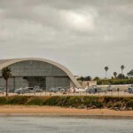Airport Inferno Jolts Gulf Aircraft hangar with helicopters near the beach.