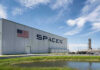 SpaceX building with American flag and launch pad.