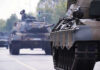 Tanks on a road with soldiers inside.