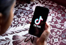 Hand holding phone showing TikTok logo.