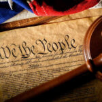 Supreme Court Shocker: Alabama Map Revived Gavel on U.S. Constitution with flag backdrop.