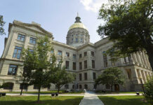 Historic building with a gold dome and surrounding trees.