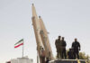 Tehran Power Grab — President Tries To Quit Military personnel beside missiles and Iranian flag.