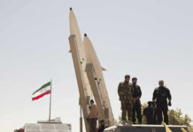 Tehran Power Grab — President Tries To Quit Military personnel beside missiles and Iranian flag.