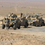 US Strike Targets Alleged Venezuelan Gang Leader Soldiers beside military vehicles in a desert area.
