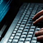 Killer Robots? UK Edges Toward Autonomy Close-up of hands typing on a laptop keyboard with code displayed on the screen