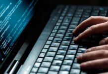 Killer Robots? UK Edges Toward Autonomy Close-up of hands typing on a laptop keyboard with code displayed on the screen