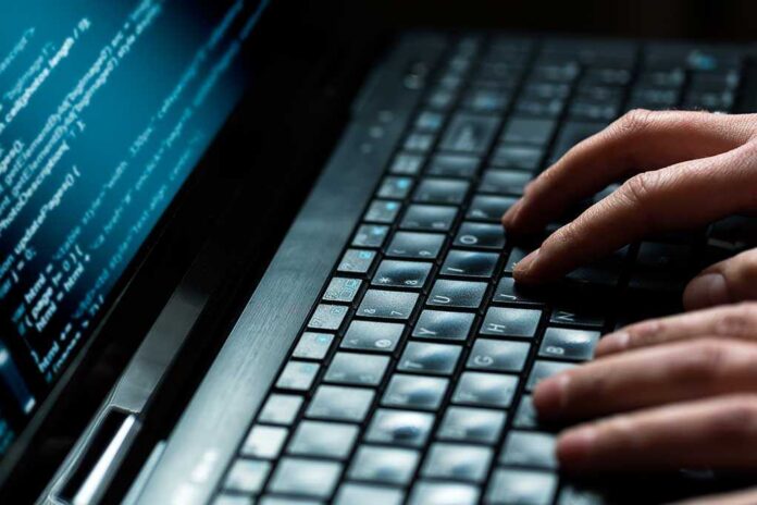 Hacker,Using,Laptop.,Lots,Of,Digits,On,The,Computer,Screen. Close-up of hands typing on a laptop keyboard with code displayed on the screen