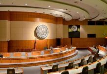 Senate Moves to Freeze Travel Funds Over Transparency Interior view of a government chamber with wooden paneling and seating