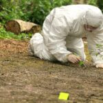 Body Found–But One Haunting Catch Forensic investigator in a protective suit collecting evidence from the ground