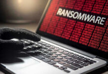 Gloved hand on laptop with ransomware screen.